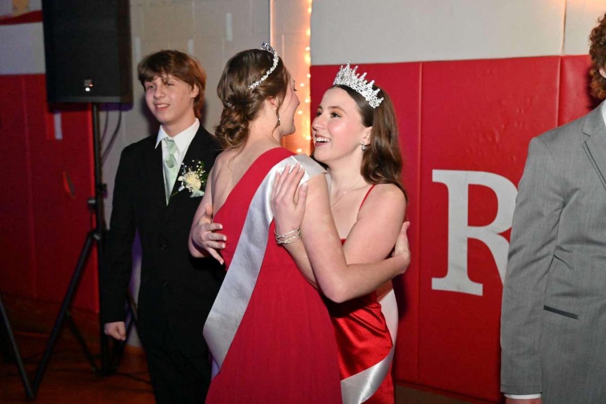 Senior Kate Harman passes on the crown to Erin Ashe, as her escort, sophomore Eli Rushton looks on. 