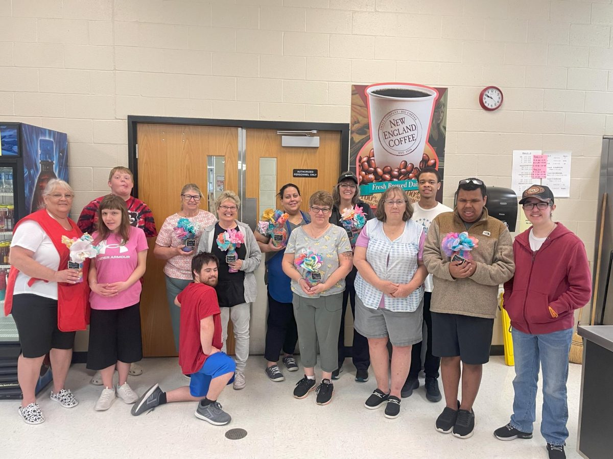 The Brew Crew poses with cafeteria staff after giving them flower bouquets they made for them.